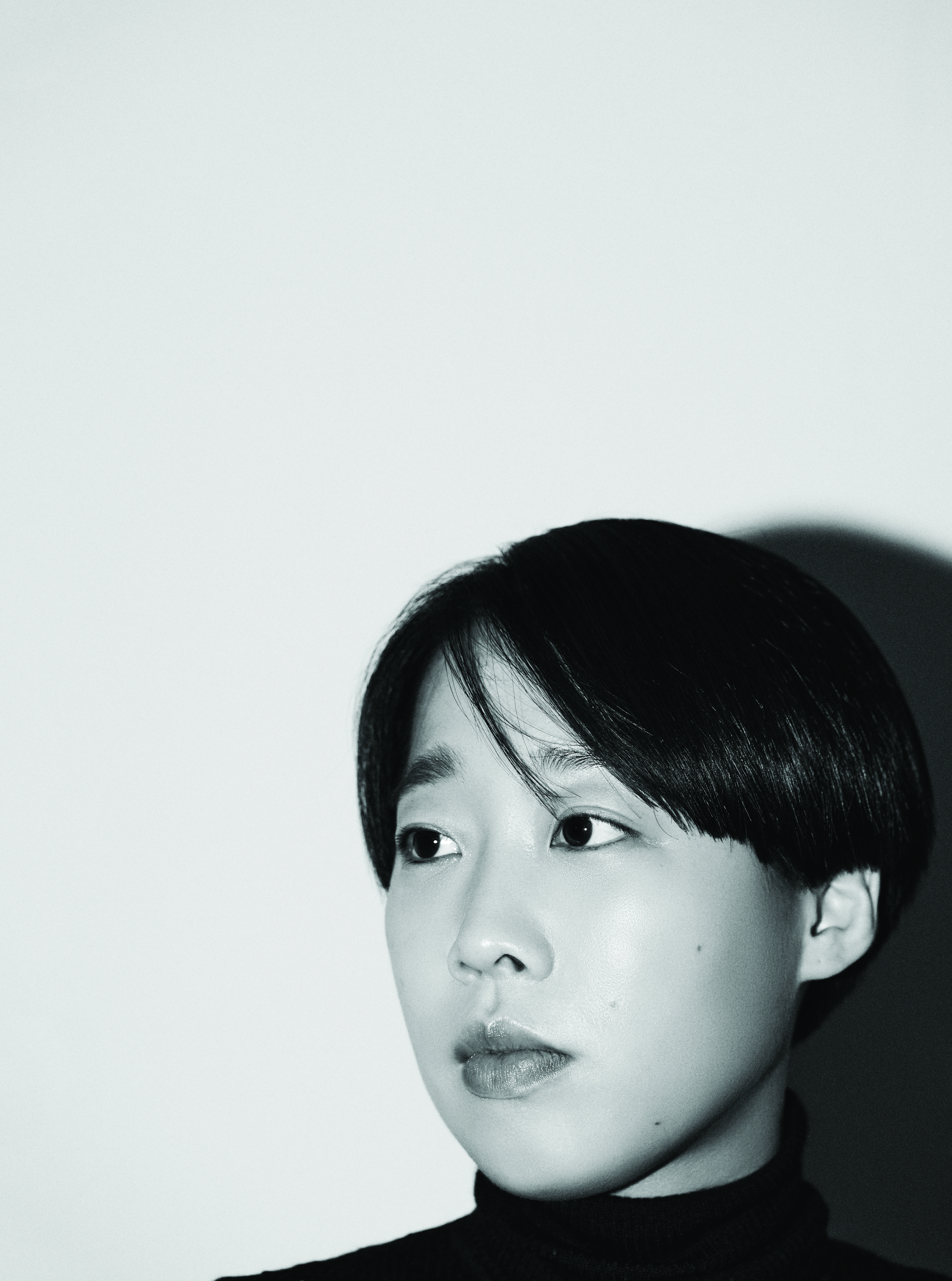 In a black-and-white photo, the black-haired, short-cut director is looking to the left.
