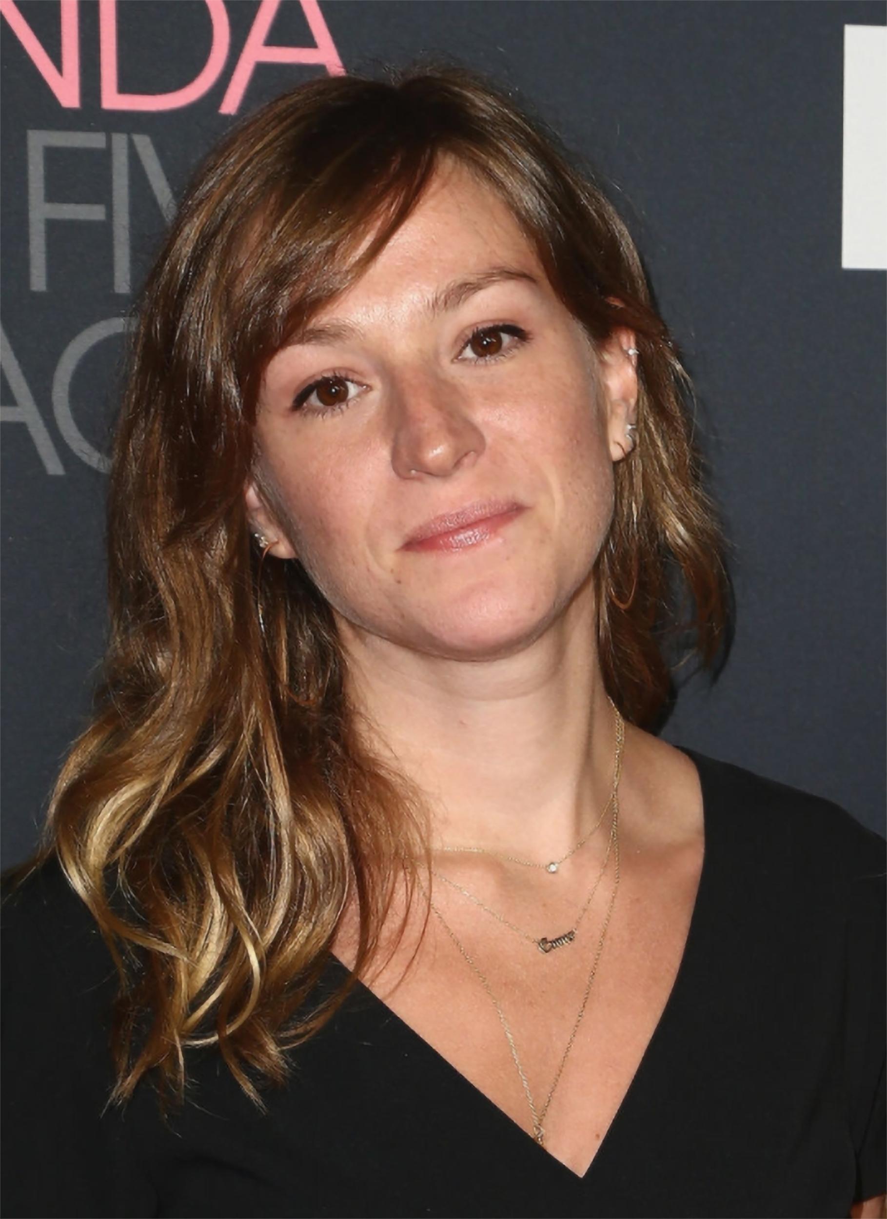 Portrait of Emma Pildes, she has medium length hair, a necklace, a v neck blouse, and her hair is slightly tilted to the left.