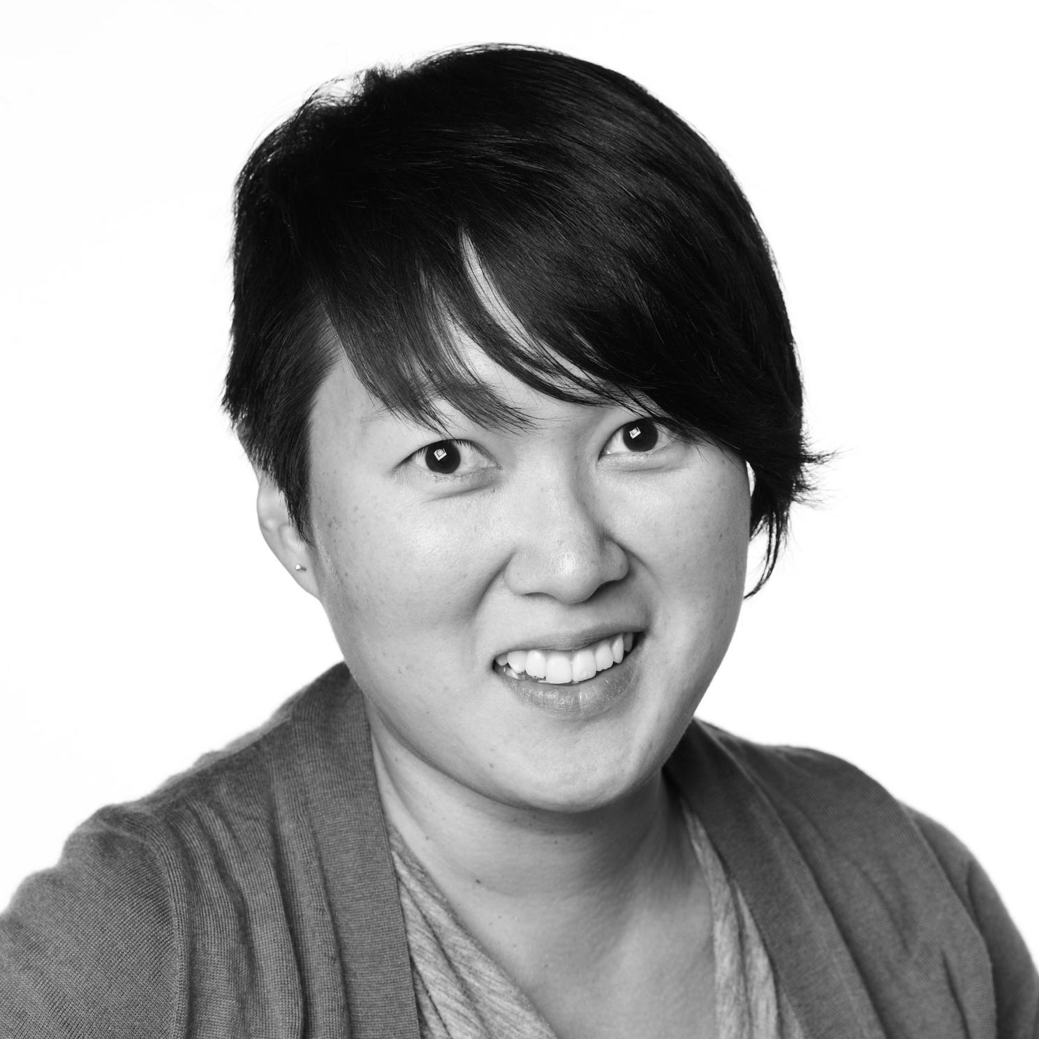 A black and white portrait of a woman smiling into the camera.