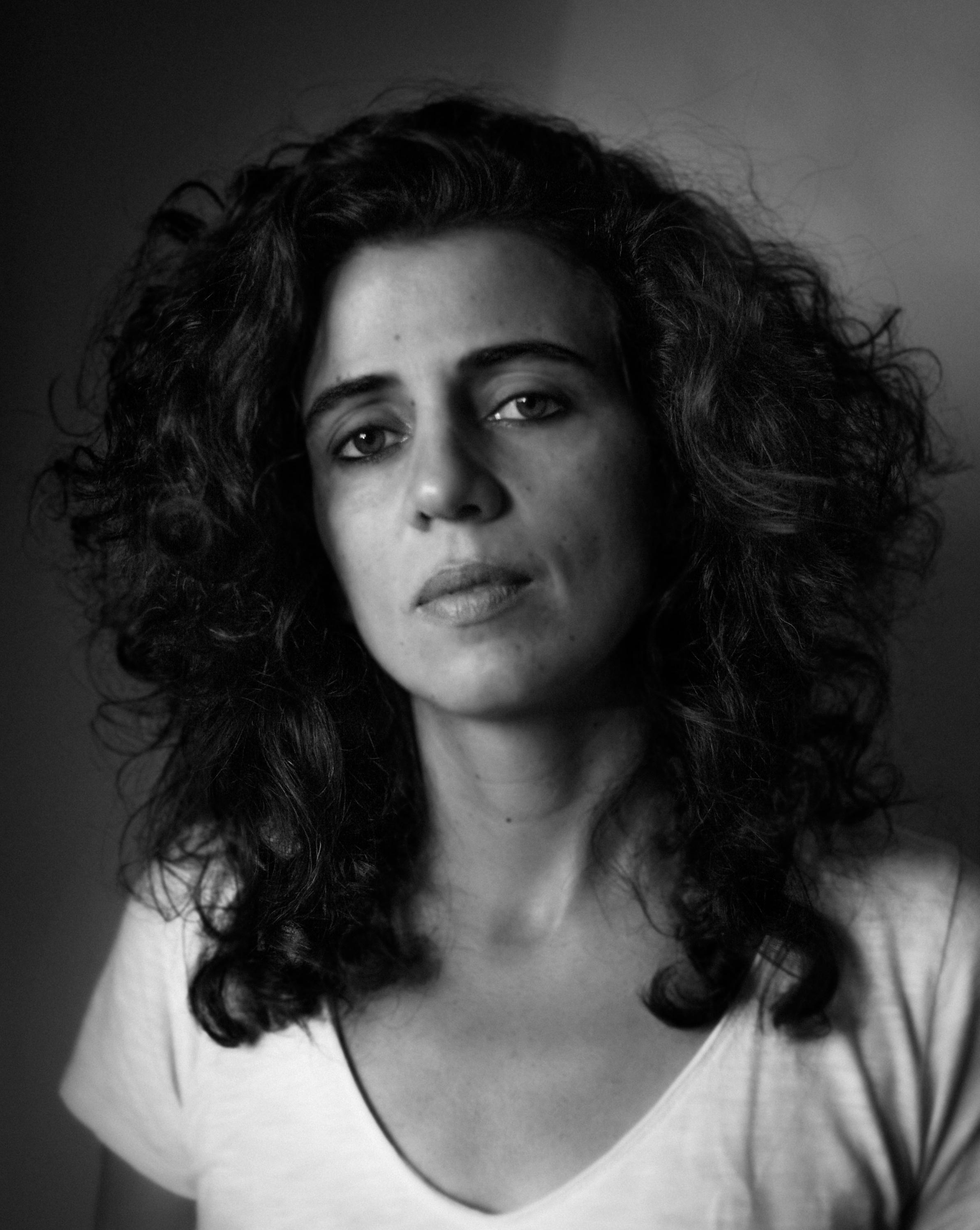 Black and white portrait of Corine Shawi looking directly at the camera.