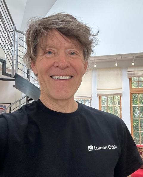 A selfie of a man with gray hair in a modern house smiling at the camera.