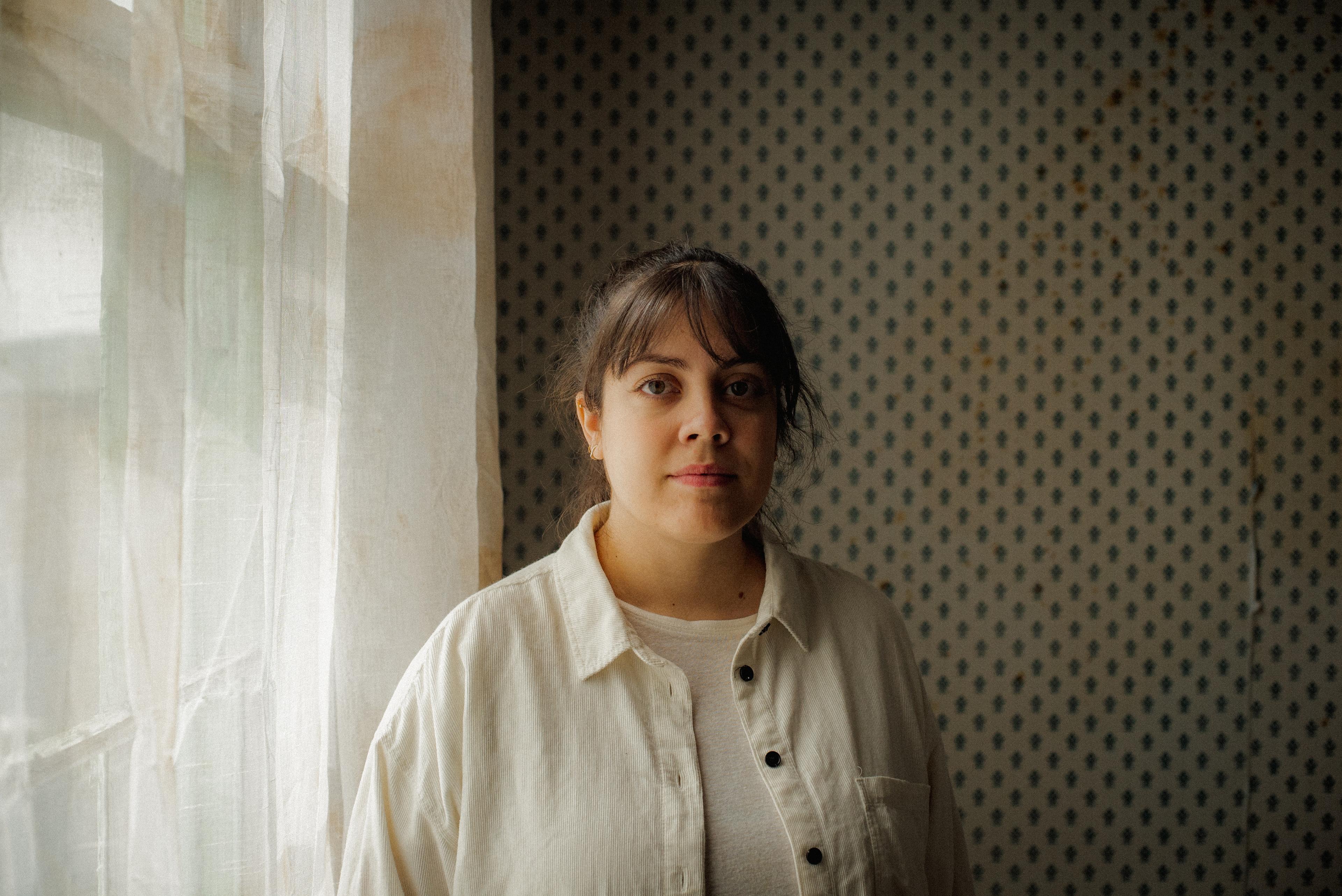 Headshot of Gabriela Pena, a woman with bangs, staring at the camera