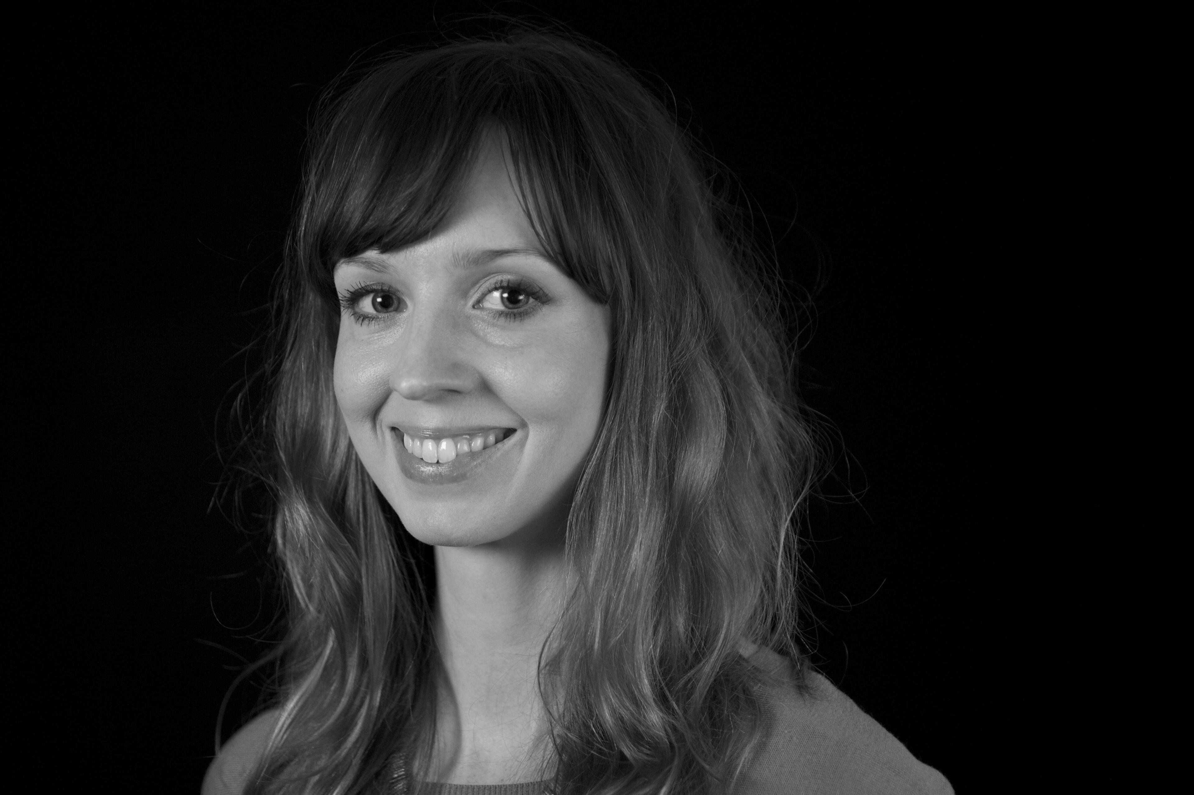 A black and white portrait of a woman smiling and looking into the camera.