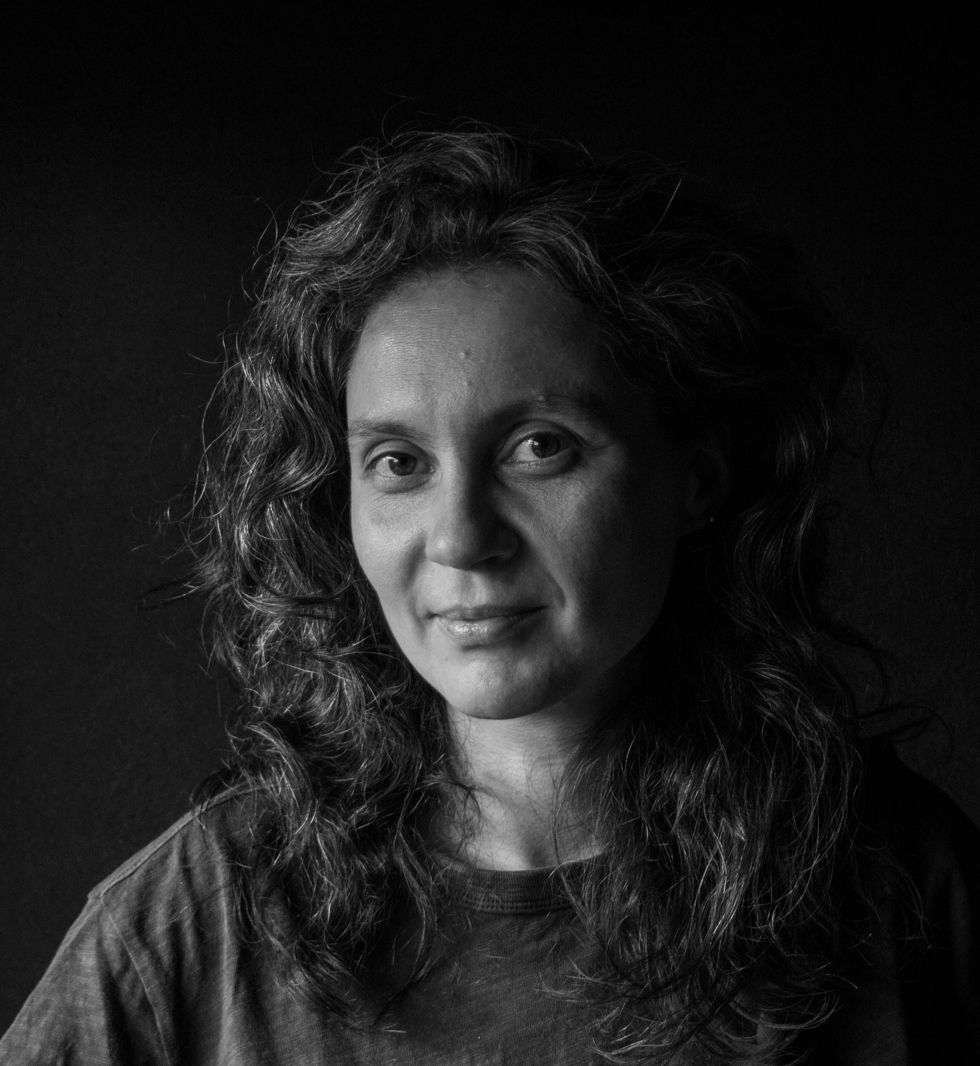 Darya Bassel looking directly at camera. She has shoulder length, wavy hair. Black and white portrait.