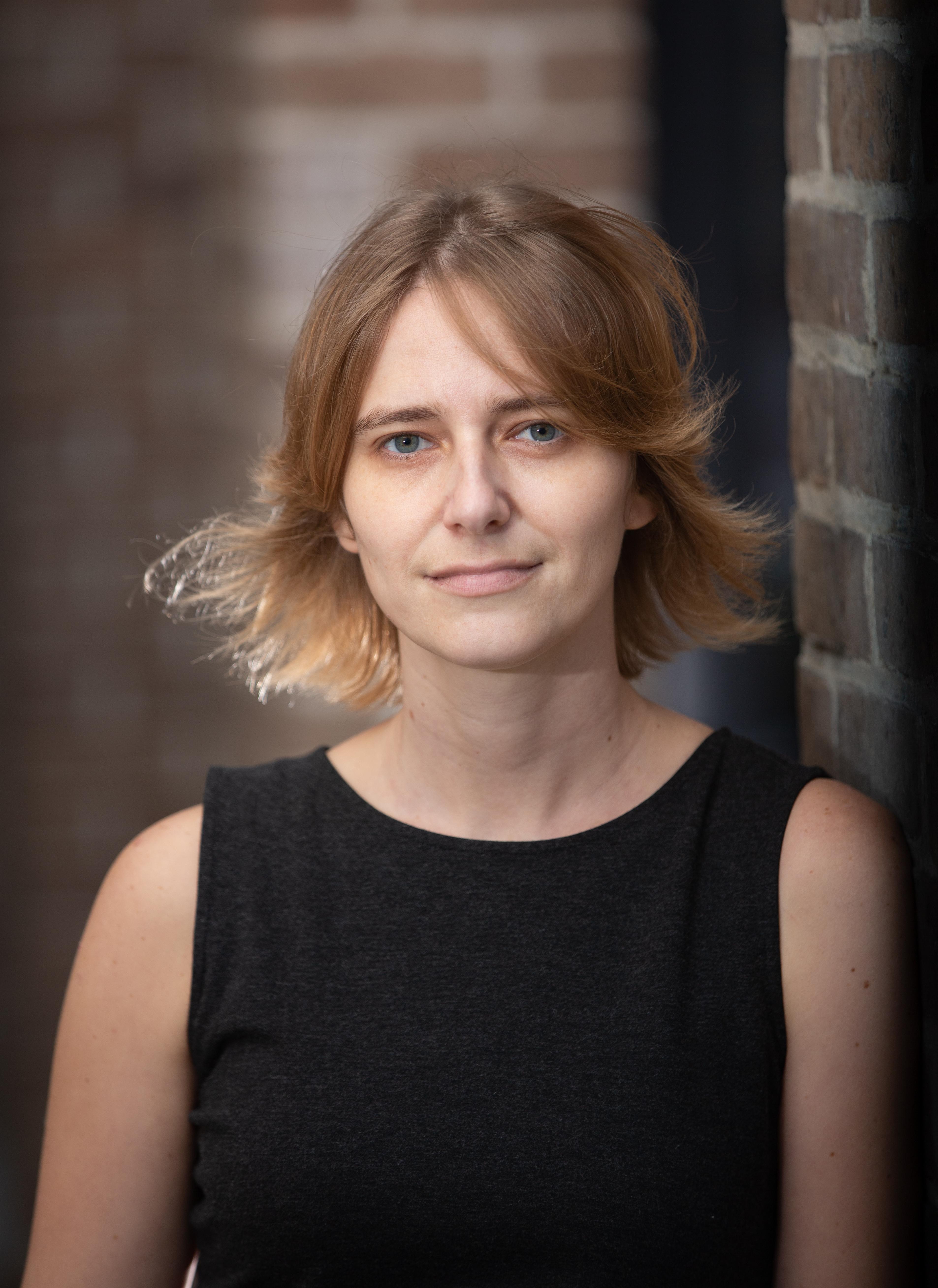 Portrait of Emily Faye Ratner, she looks at the camera, has short hair and sleeveless shirt.