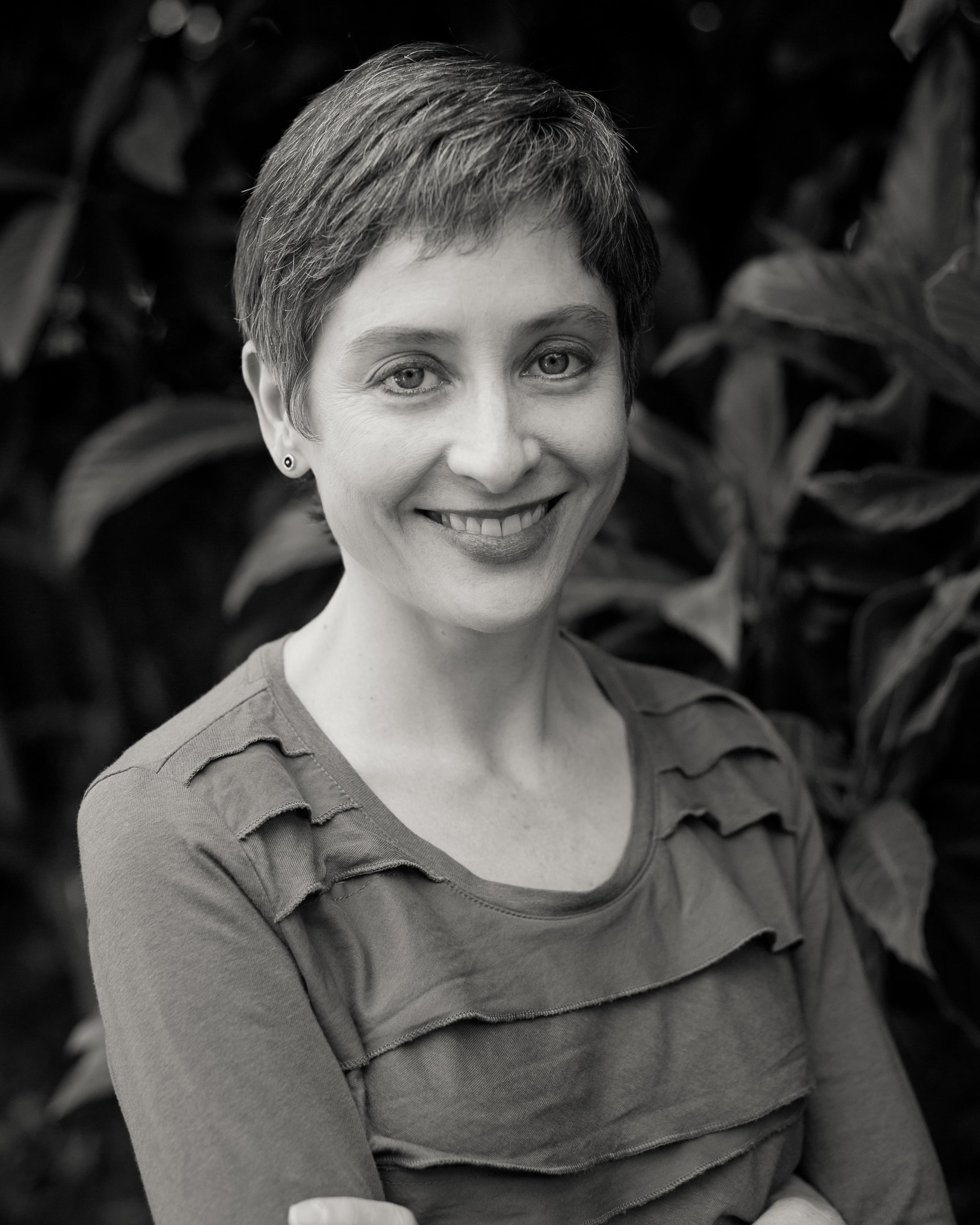 Gabriela Quirós looks at the camera smiling. She has short hair. Photo is in Black and White.