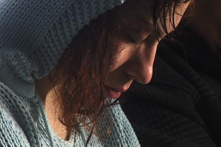 A closeup of a woman wearing a matching knit blue hat and sweater closing her eyes.