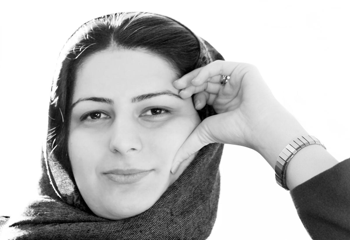 Rokhsareh Ghaemmaghami Smiles at the camera with a hand on her head. The photo is in Black and White.