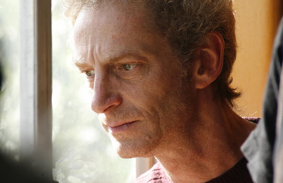 Photo of a man looking out of a window.