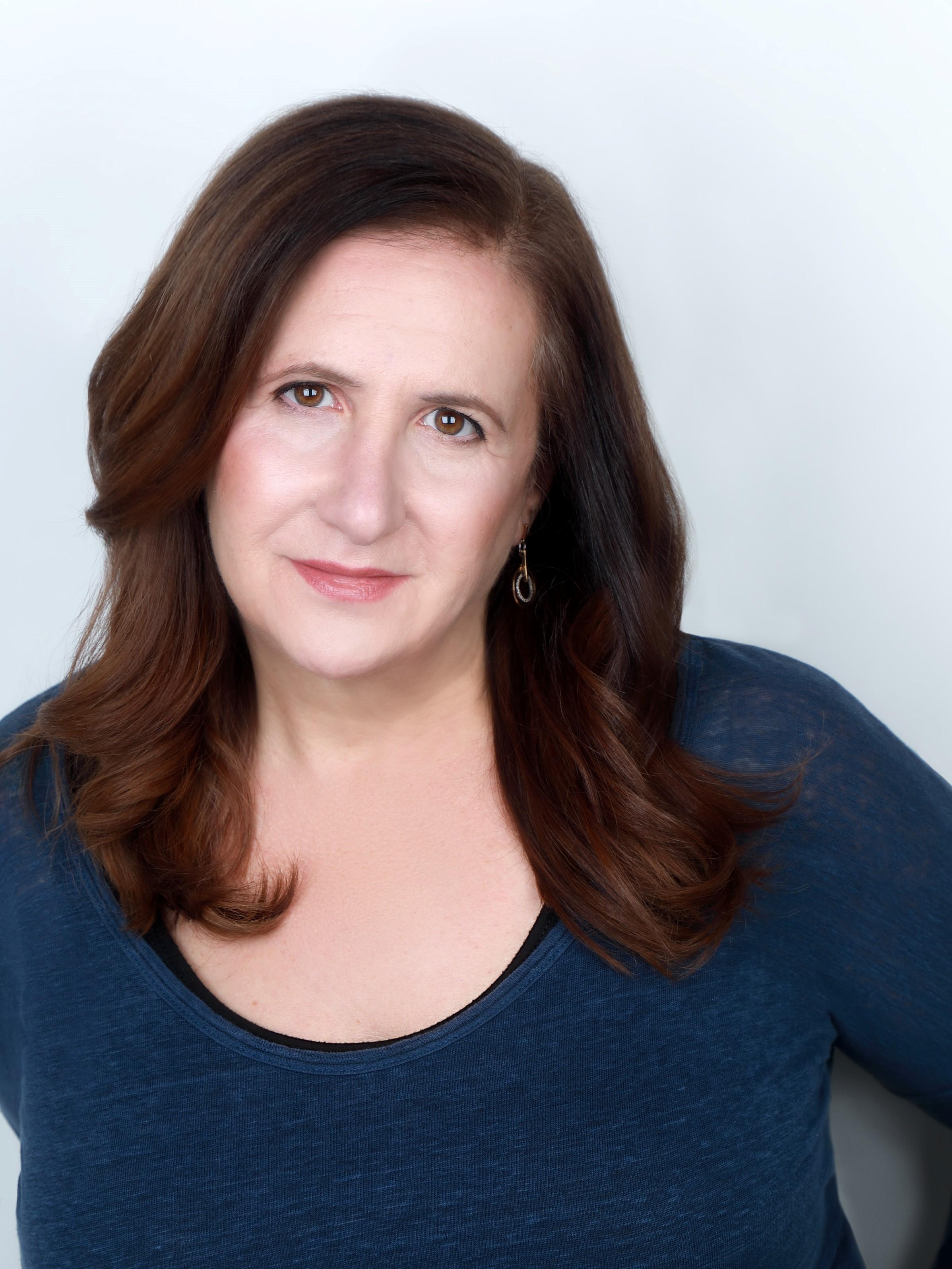 Portrait of Tia Lessin, she wears a long-sleeve shirt, medium length hair and looks at the camera