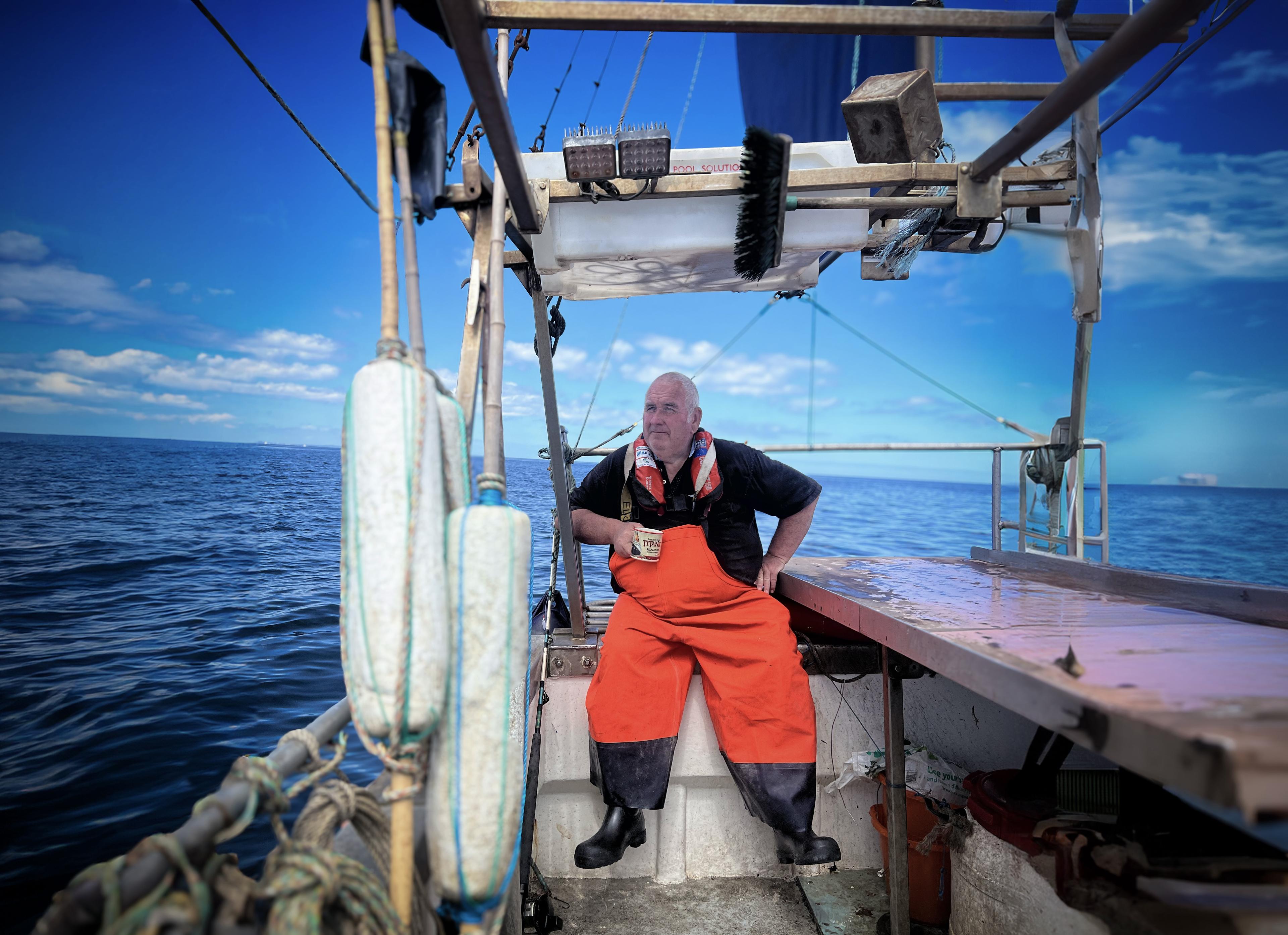 Still of All Rivers Spill Their Stories To The Sea. A fisherman on a boat in the ocean.